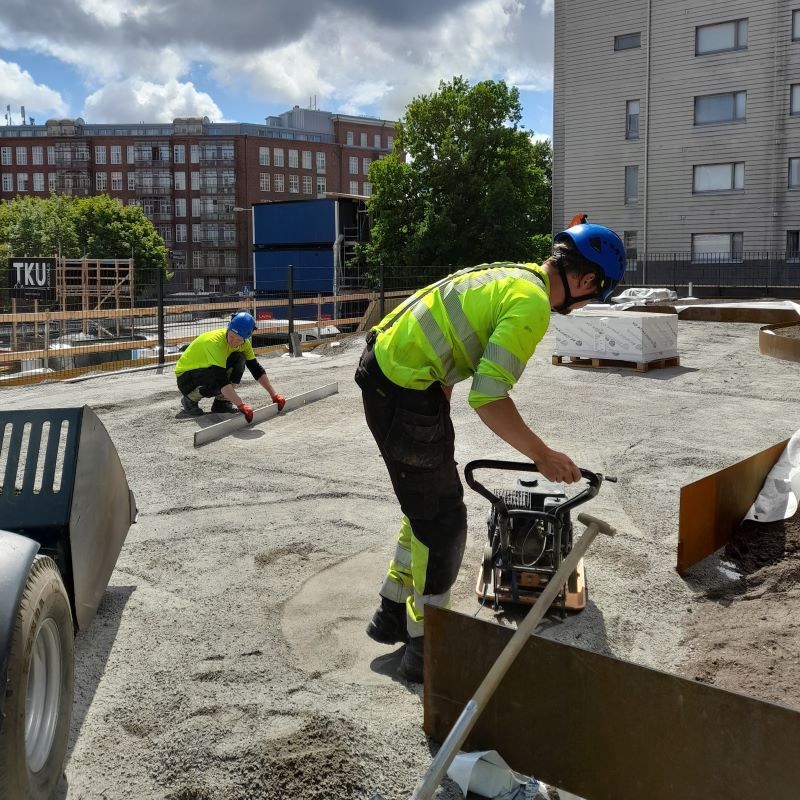 Viherrakentajat rakentavat istutusaltaita pihalla ja tasoittavat kivituhkaa lanalla ja täryllä.